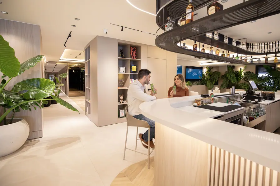 Curved lobby bar with bottles and guests seated nearby.