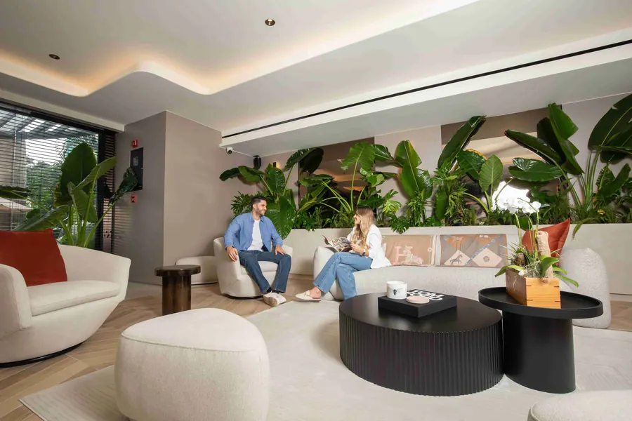 Guests talking in the lobby lounge with plants and low tables.
