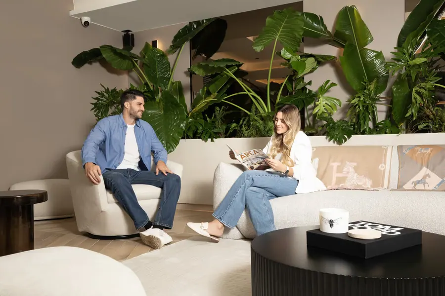 A couple relaxing on a sofa in the lobby lounge, surrounded by plants.