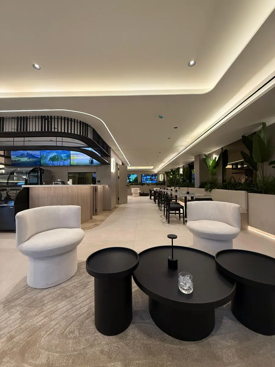 Lobby lounge with white armchairs, low black tables and plants.