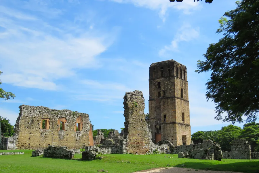Cathedral bell tower and stone ruins at Panama Viejo, green lawn, blue sky