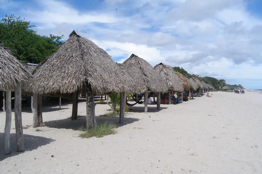 Row of palm-thatched shelters on the white sand of Santa Clara beach