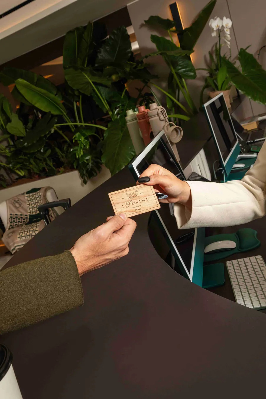 Hands passing a room card at the reception desk.