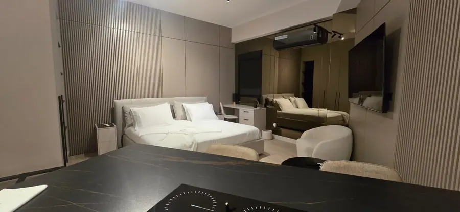 The Corner Suite bed, desk and kitchen in the background.